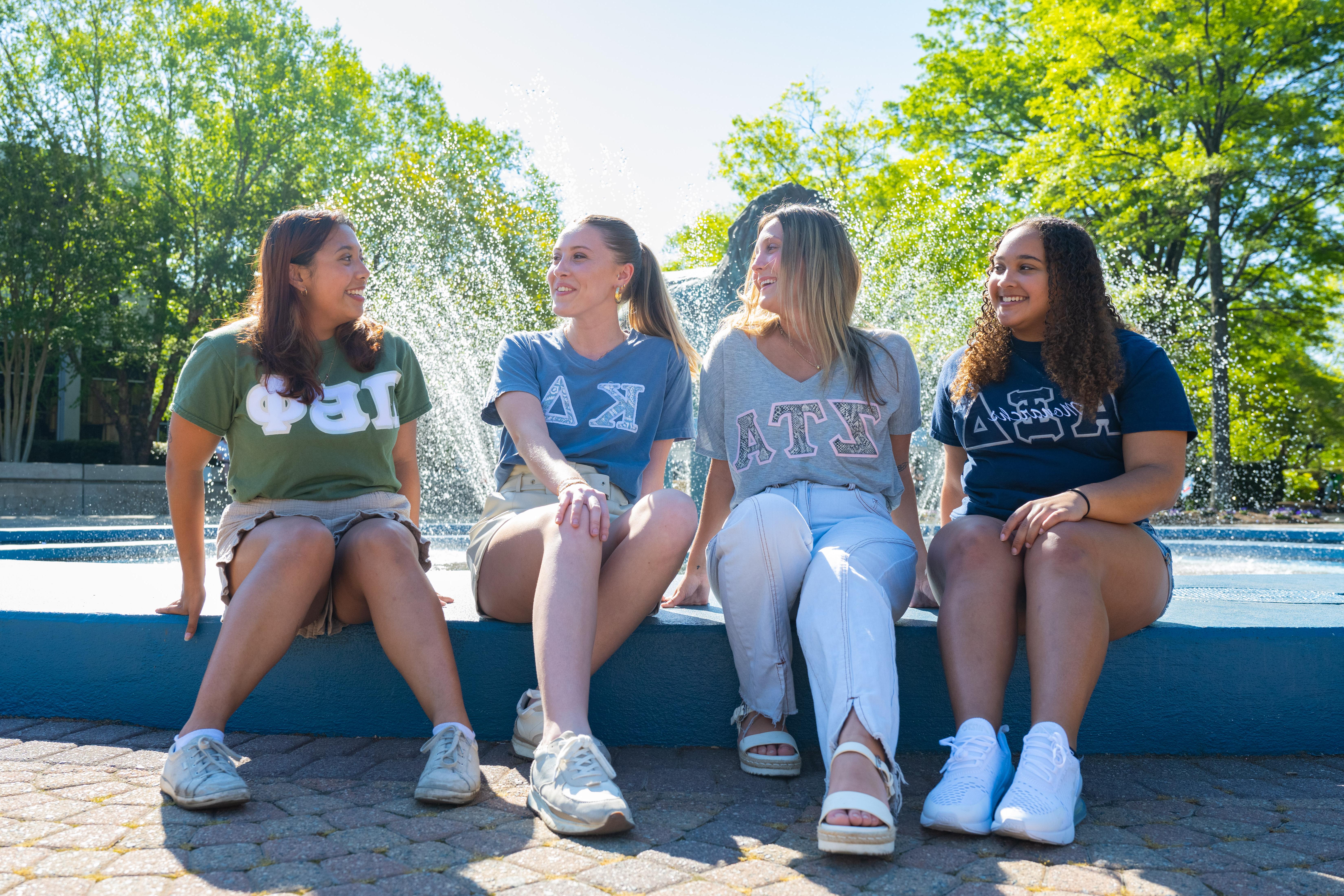 Sorority members sit in front of fountain